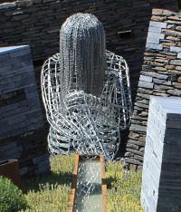 Sculpture of young woman hanging her head down made from chains